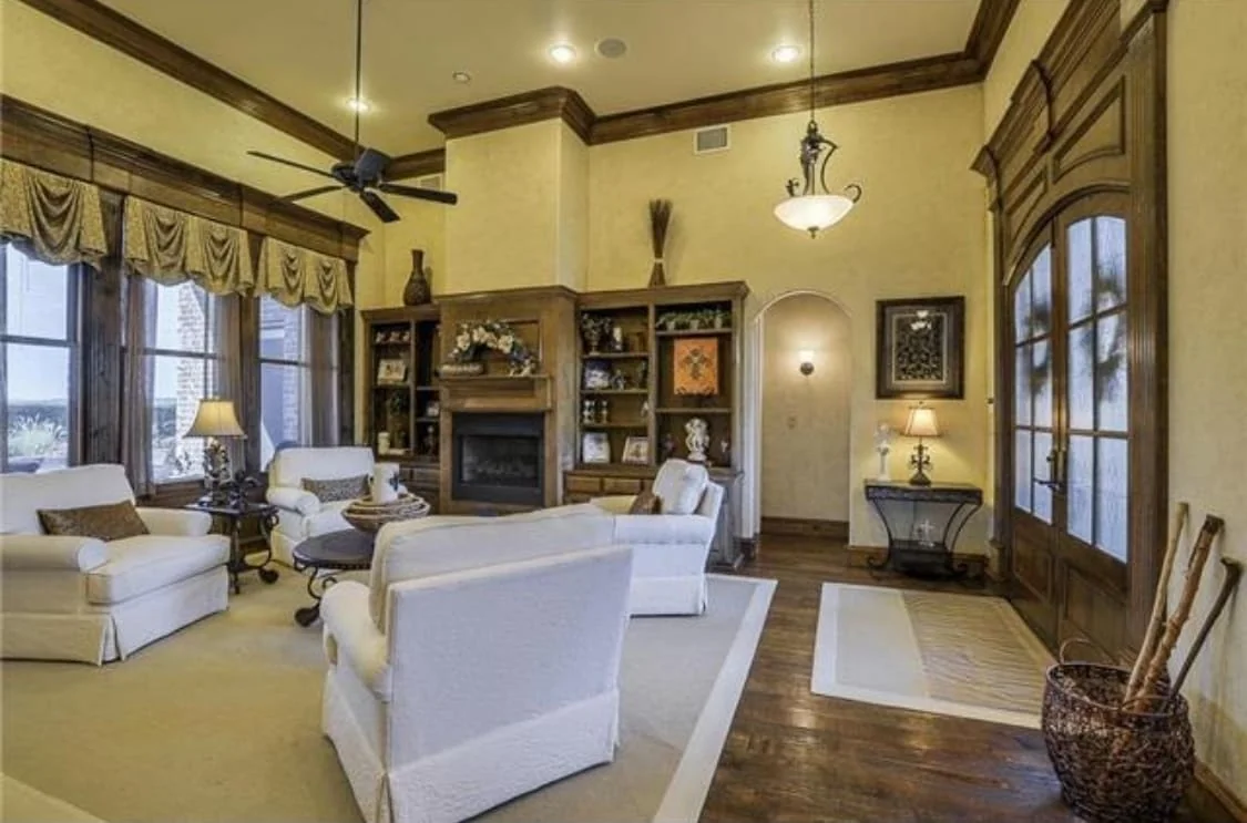 Double-height living room with exposed beams, a stone fireplace and large windows